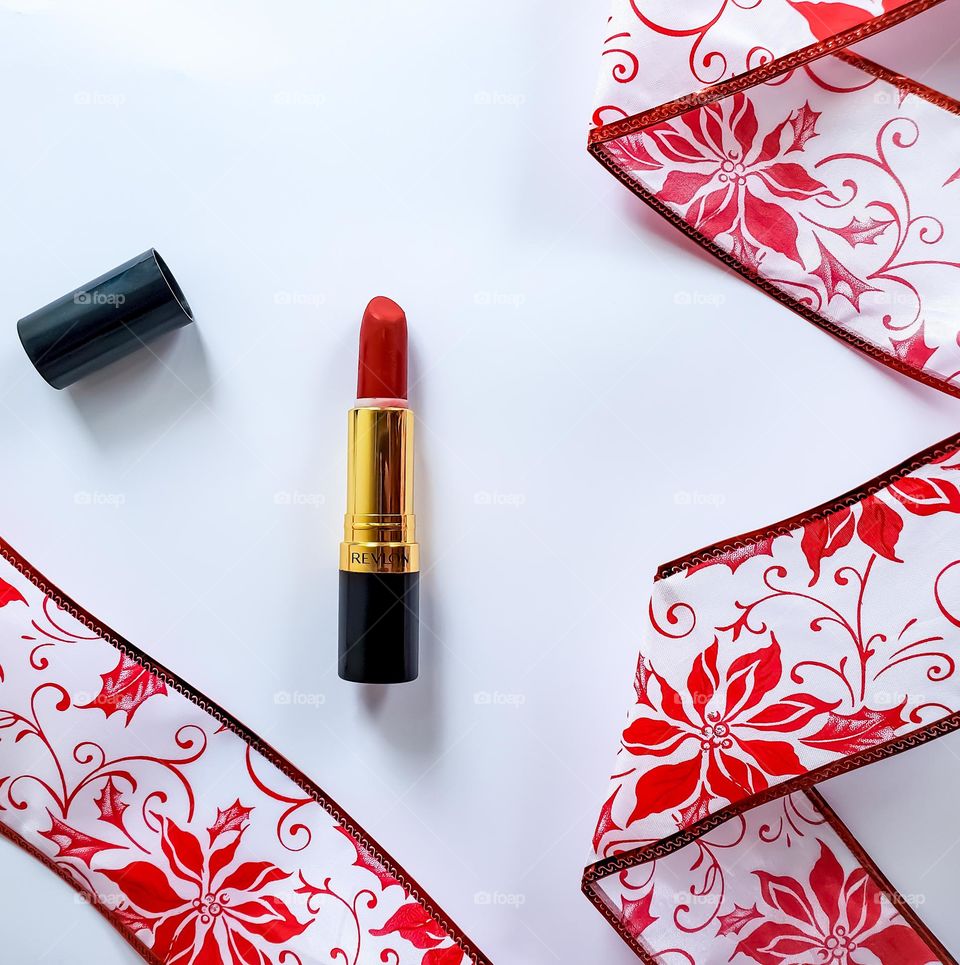 A vivacious red lipstick flatlay in a red and white holiday inspired theme.