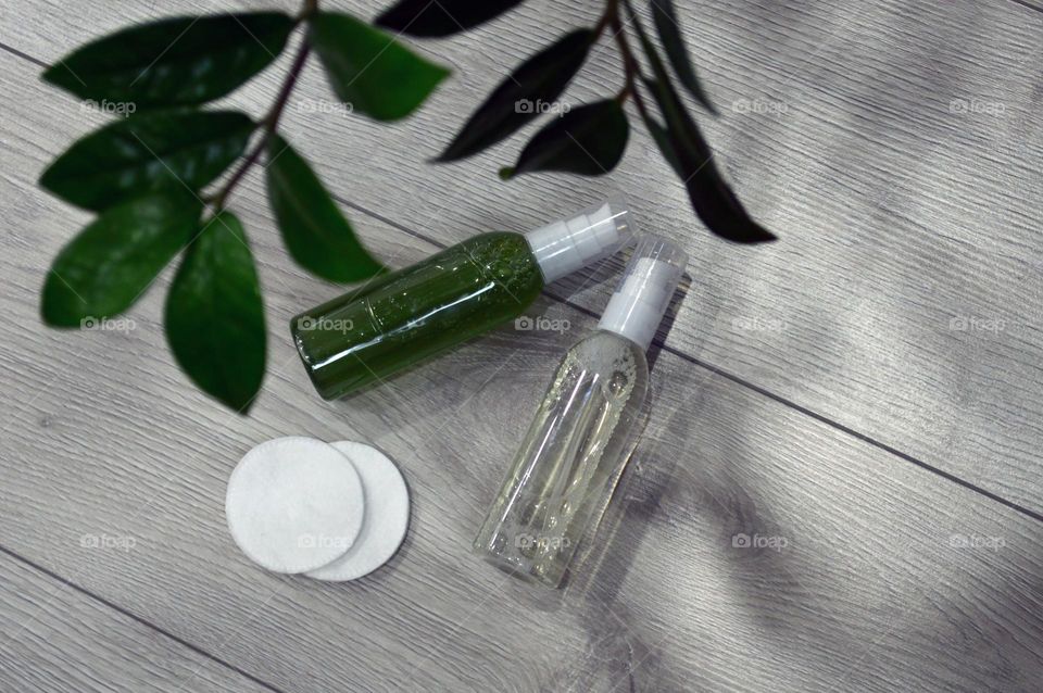 Jars with cream, shampoo and cosmetics on a background with green plants