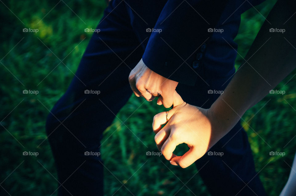 Couple holding hands. The man holds the adult woman's finger.