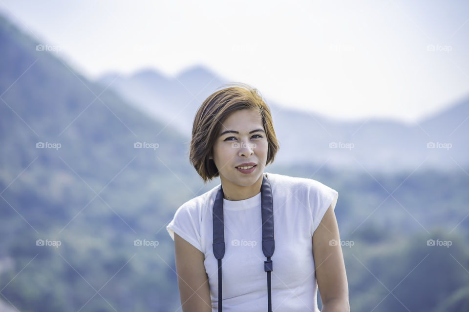 Portrait of Women with short hair brown skin background mountains and trees.