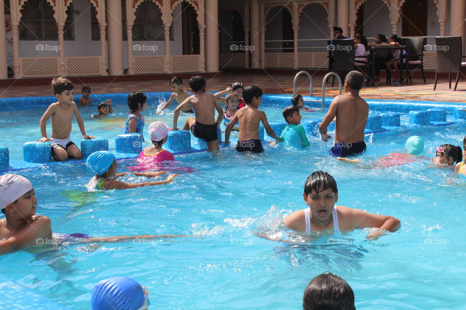 Sweet little boy, swimming in big swimming pool, summertime.