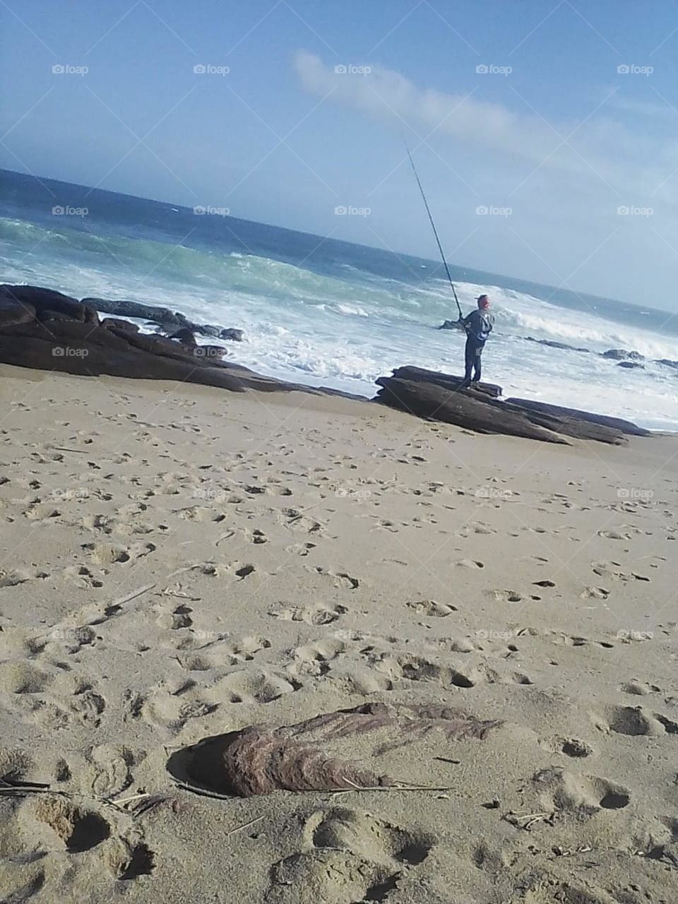 A fisherman on a Rocky beack