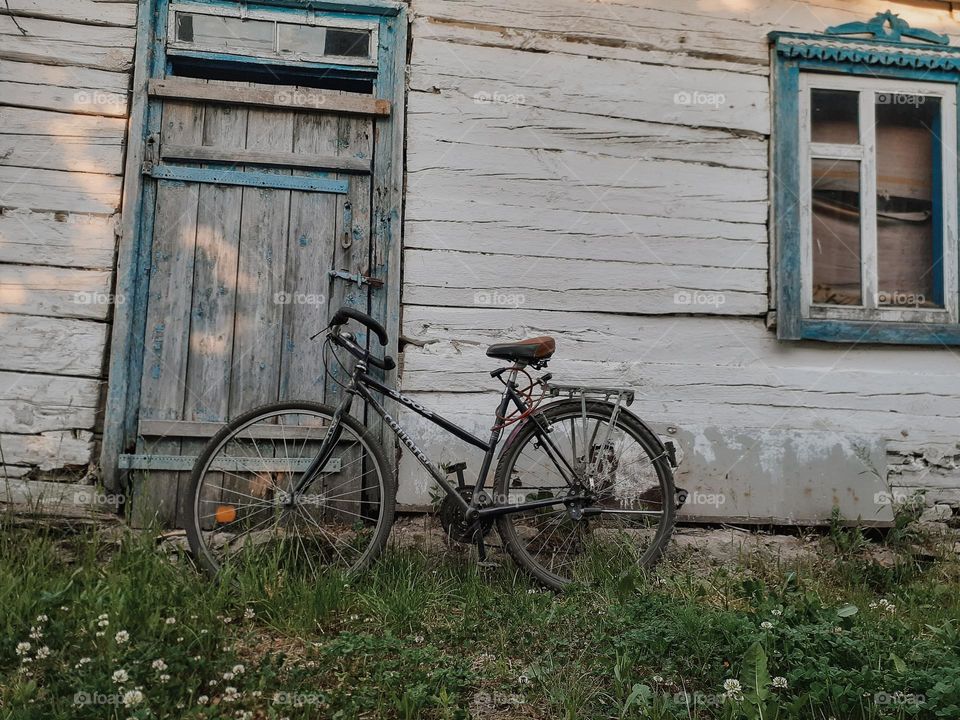 A sad photo of a sports bicycle standing under a grandmother's country house