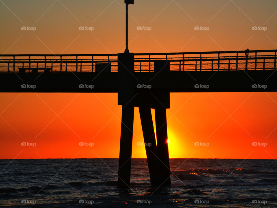 Silhouette of bridge over sea at sunset