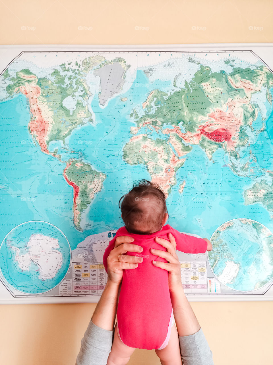 Mother hand holding little baby in front of map