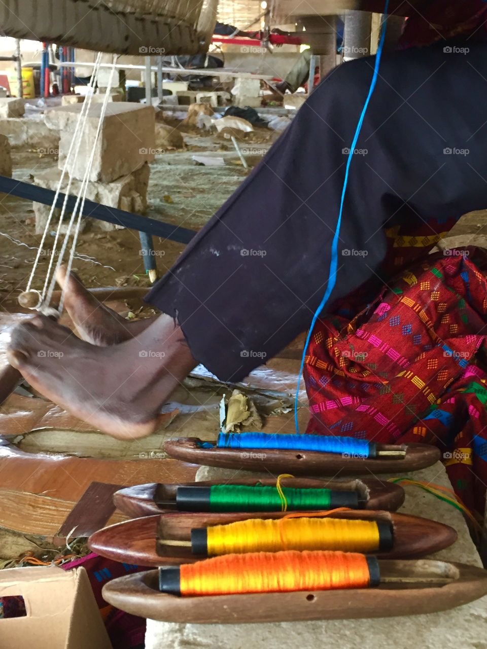 Weaver's feet at the loom with a bowl of thread