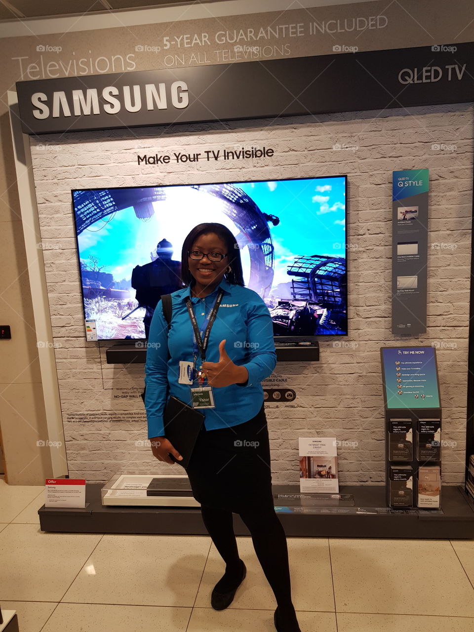 Woman posing in front of the Samsung QLED television 4K UHD TV with soundbar