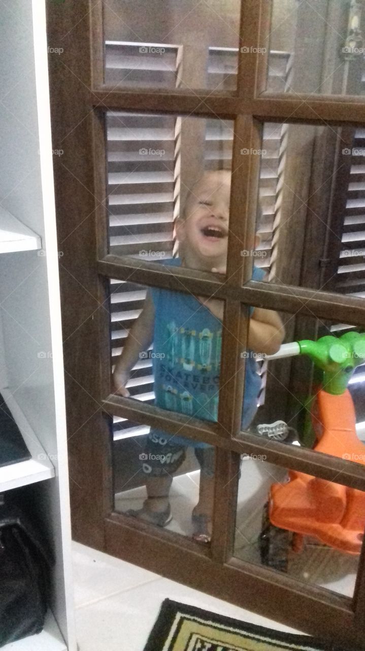 Happy boy standing in front of glass door in home