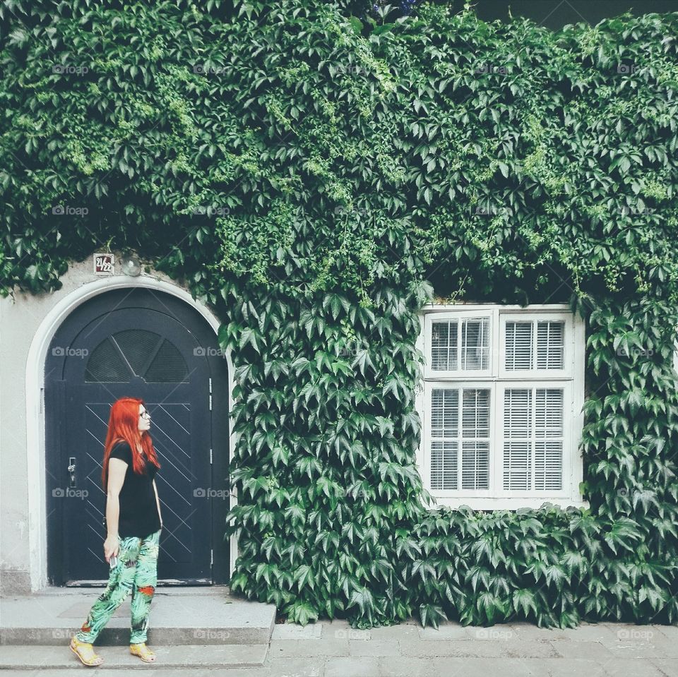 Woman standing in front of house decorated with vine