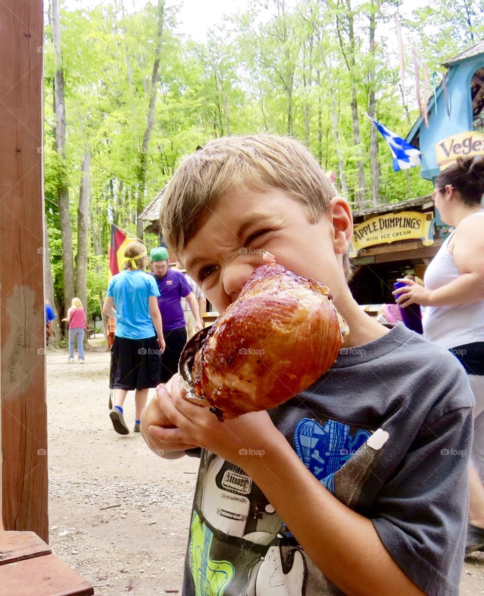 Medieval fest, child eating large turkey leg