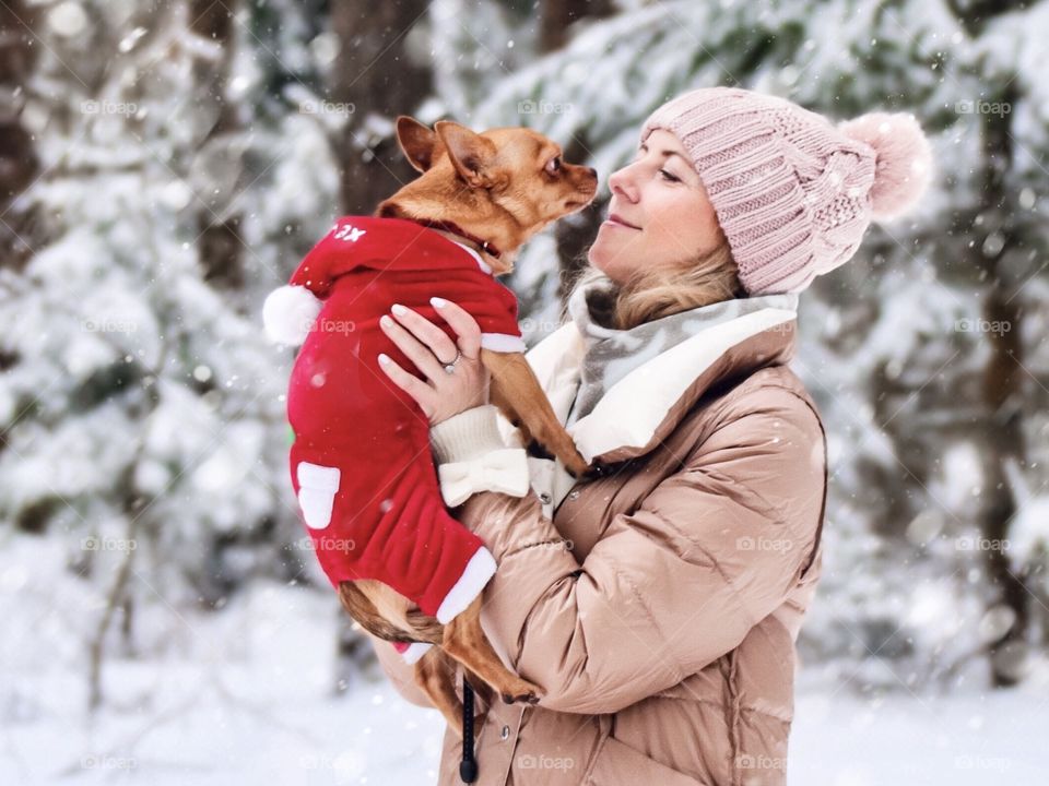 Winter forest. Woman with small dog 