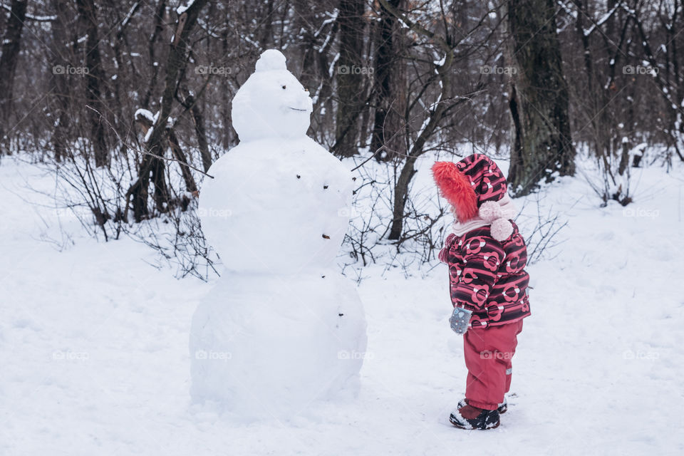 baby and snowman in the winter forest