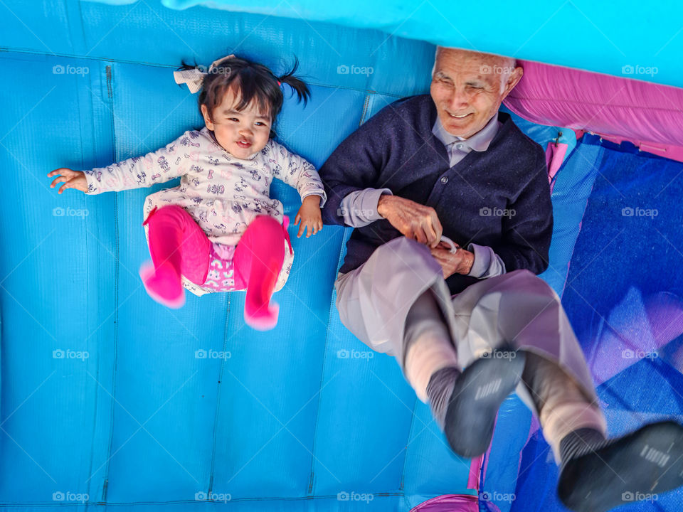 Grandfather and granddaughter playing in the inflatable bounce.