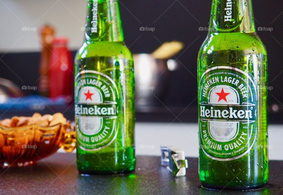 Heineken beer bottles with pasta cooking in the background.