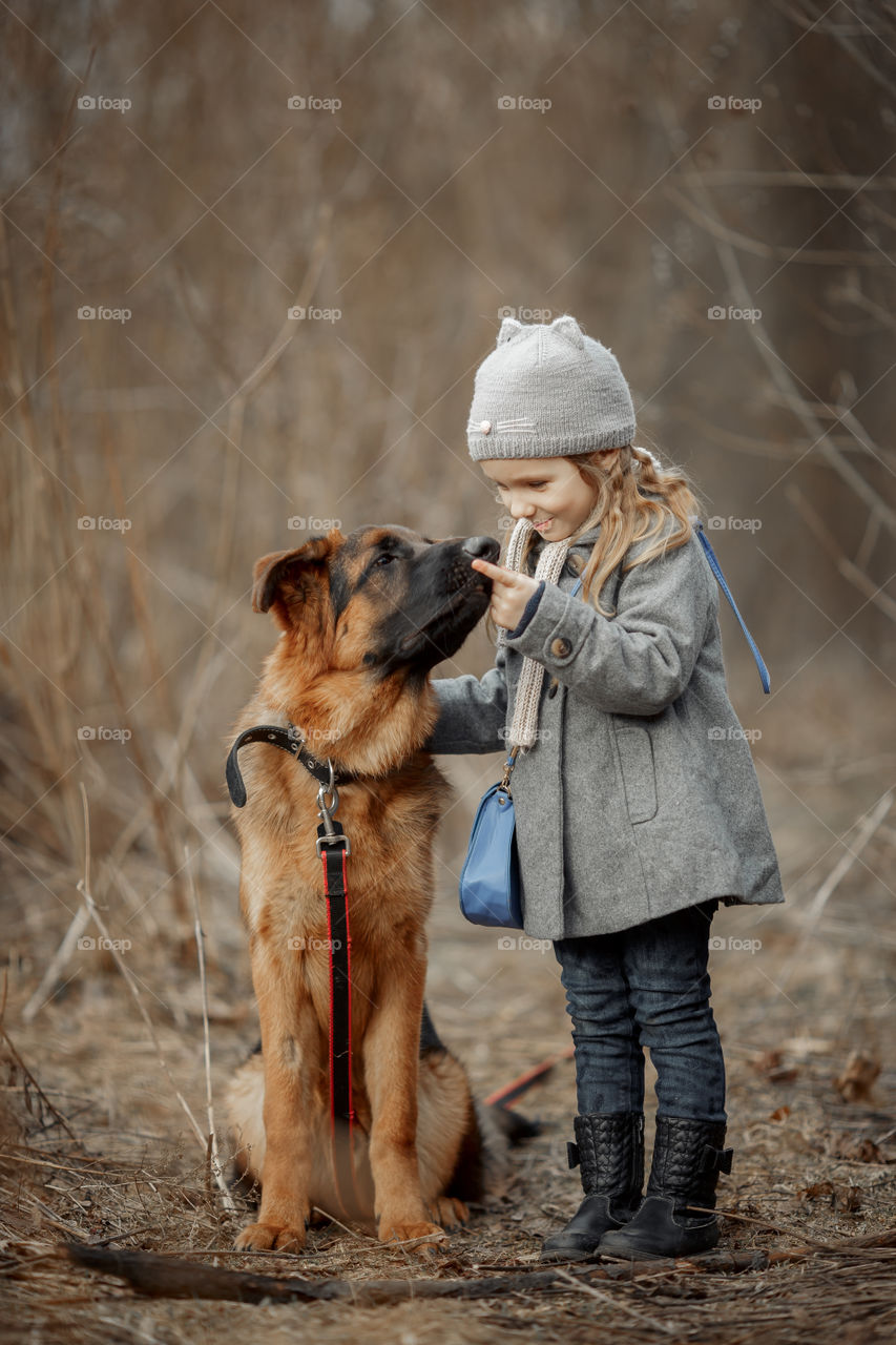 Little girl with German shepherd young male dog walking outdoor at spring day