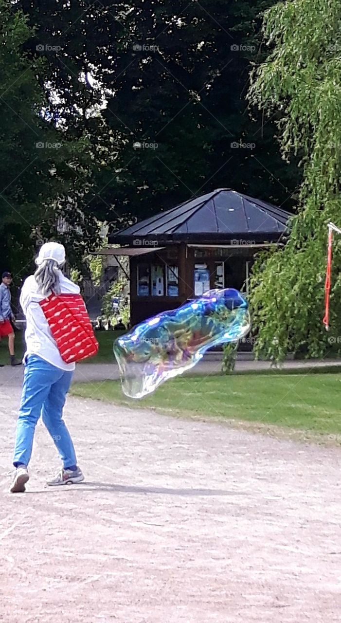 People in the park with a big soap bubble