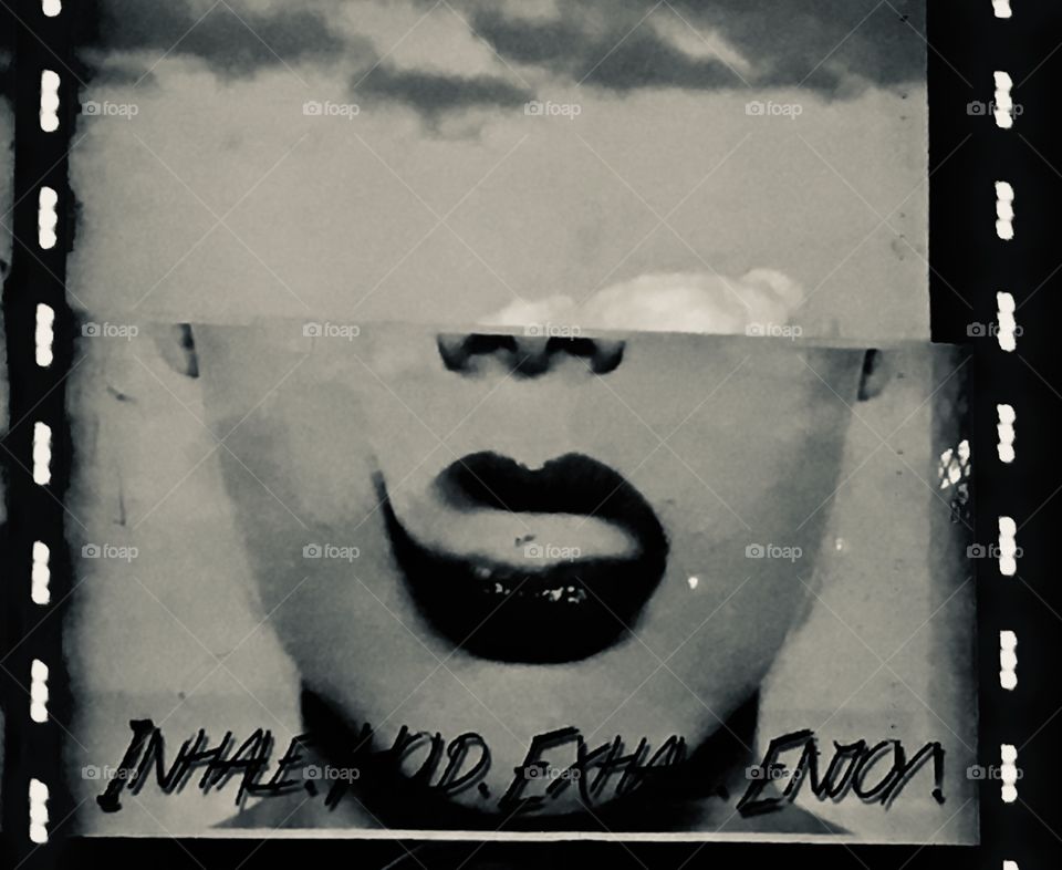 Lips and nose exhaling clouds with the perfect cloud reflection in a vape window sign in Orlando, Florida in black and white.