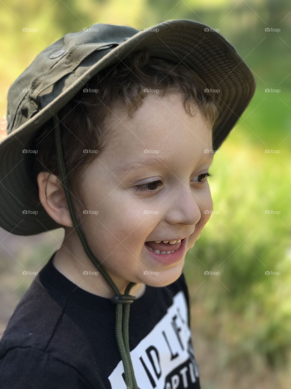 A delighted young boy with a bony hat in a field in the woods on a hike in Central Oregon on a sunny summer day. 