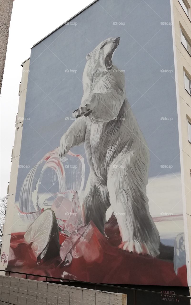 A huge painting of a polar bear on the wall of a apartment building. An angry beast is standing on its two feet and the mouth is open.
