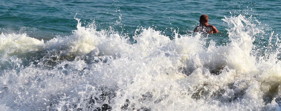 Water splashing in the sea and a man swimming