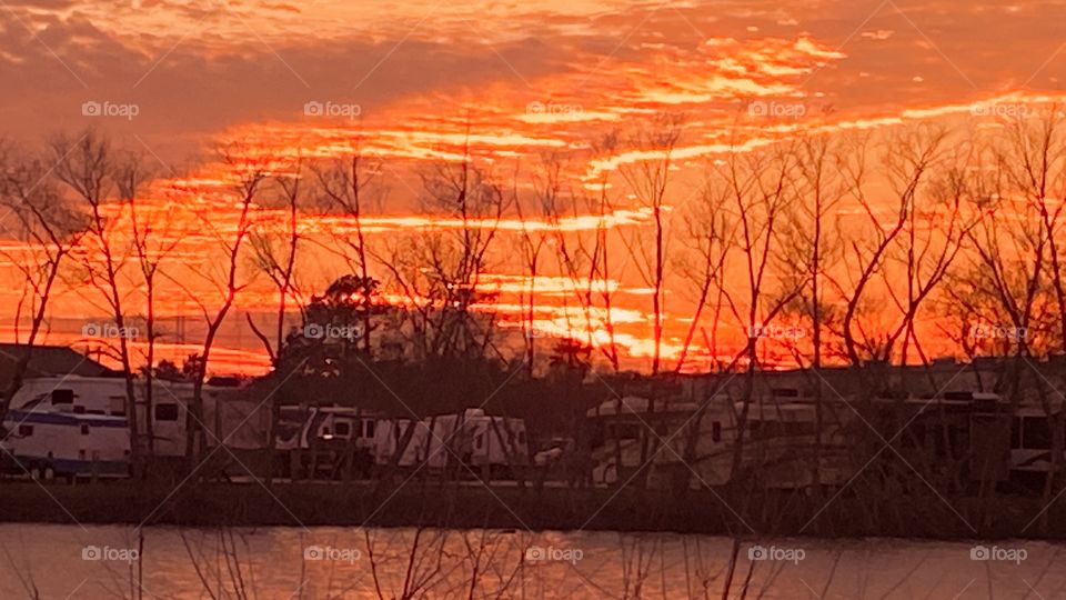 Sundown Completed Twilight is full swing. Orange Silhouettes with cloud breaks. Jaggered ends to the clouds makes interesting views. Winterized Trees Leafless from Seasonal Cold Temps.