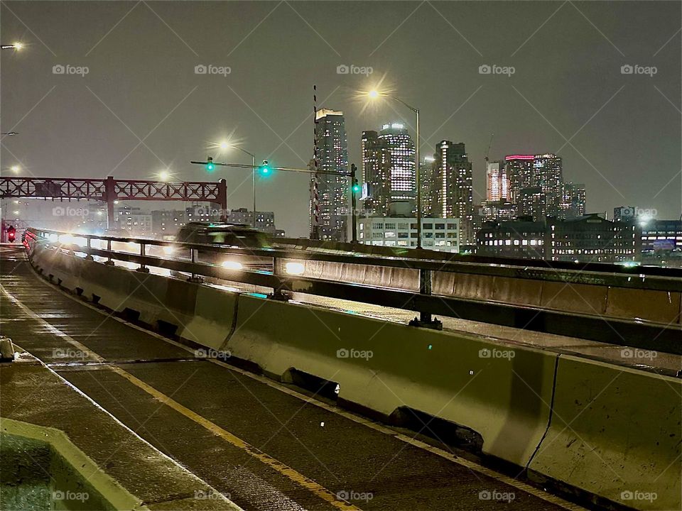 This is the evening traffic on the “Pulaski Bridge” at “Newtown Creek” connecting “Greenpoint”, Brooklyn to LIC, Queens. The cars are zooming by nearly incessantly lighting up the darkness with their bright headlights. 2023. Hypnotic Productions