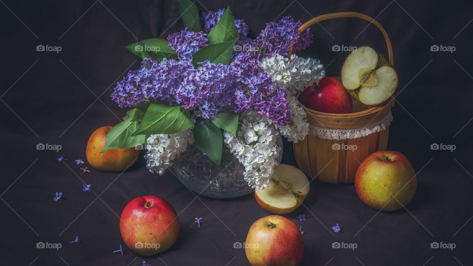 still life of apples and lilacs on a dark background