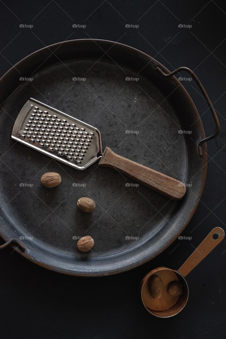 Nutmeg on metal tray with wooden handle grater. (Metal vs wood).