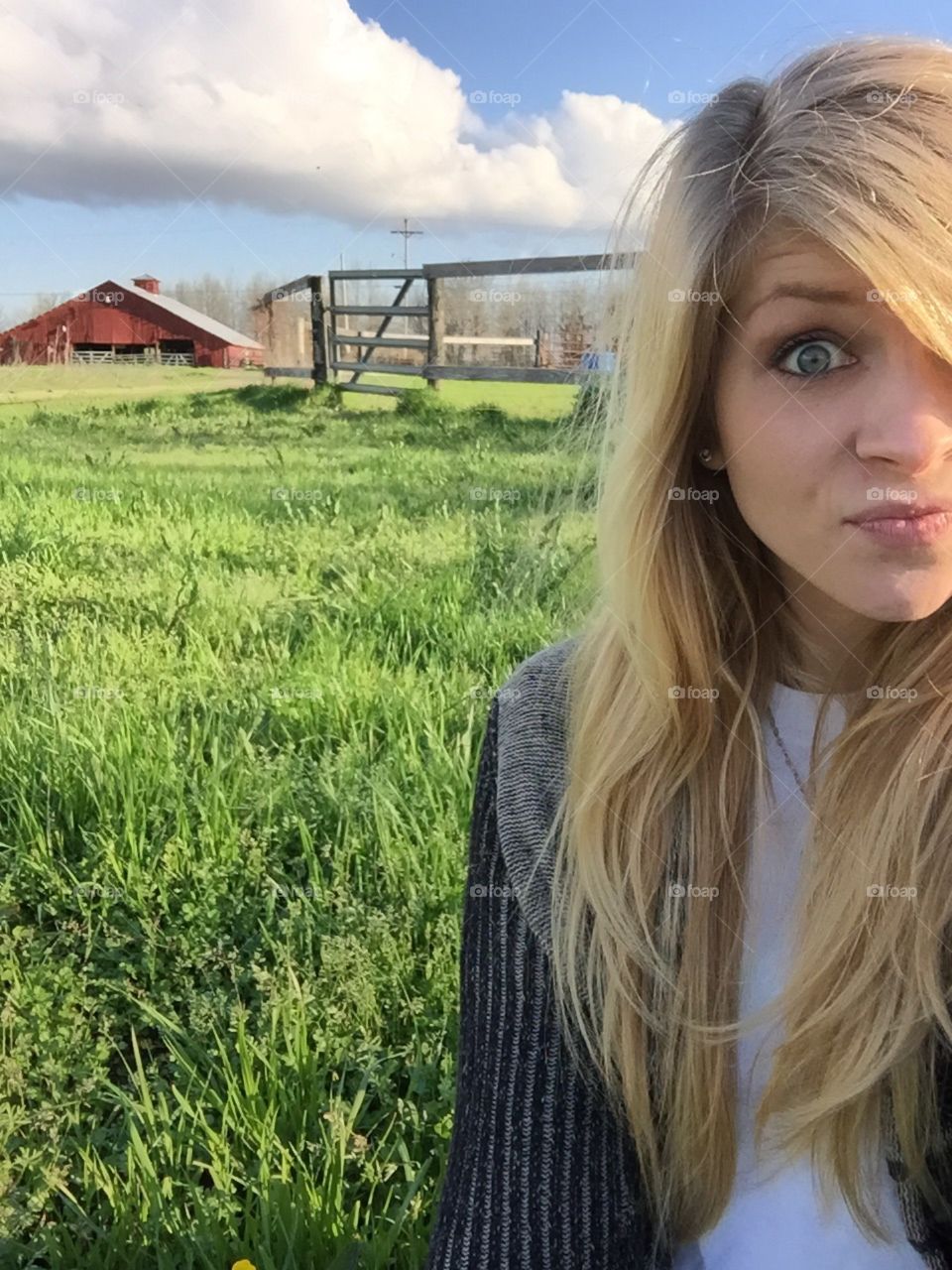 Blonde girl sitting in the grass at the barn