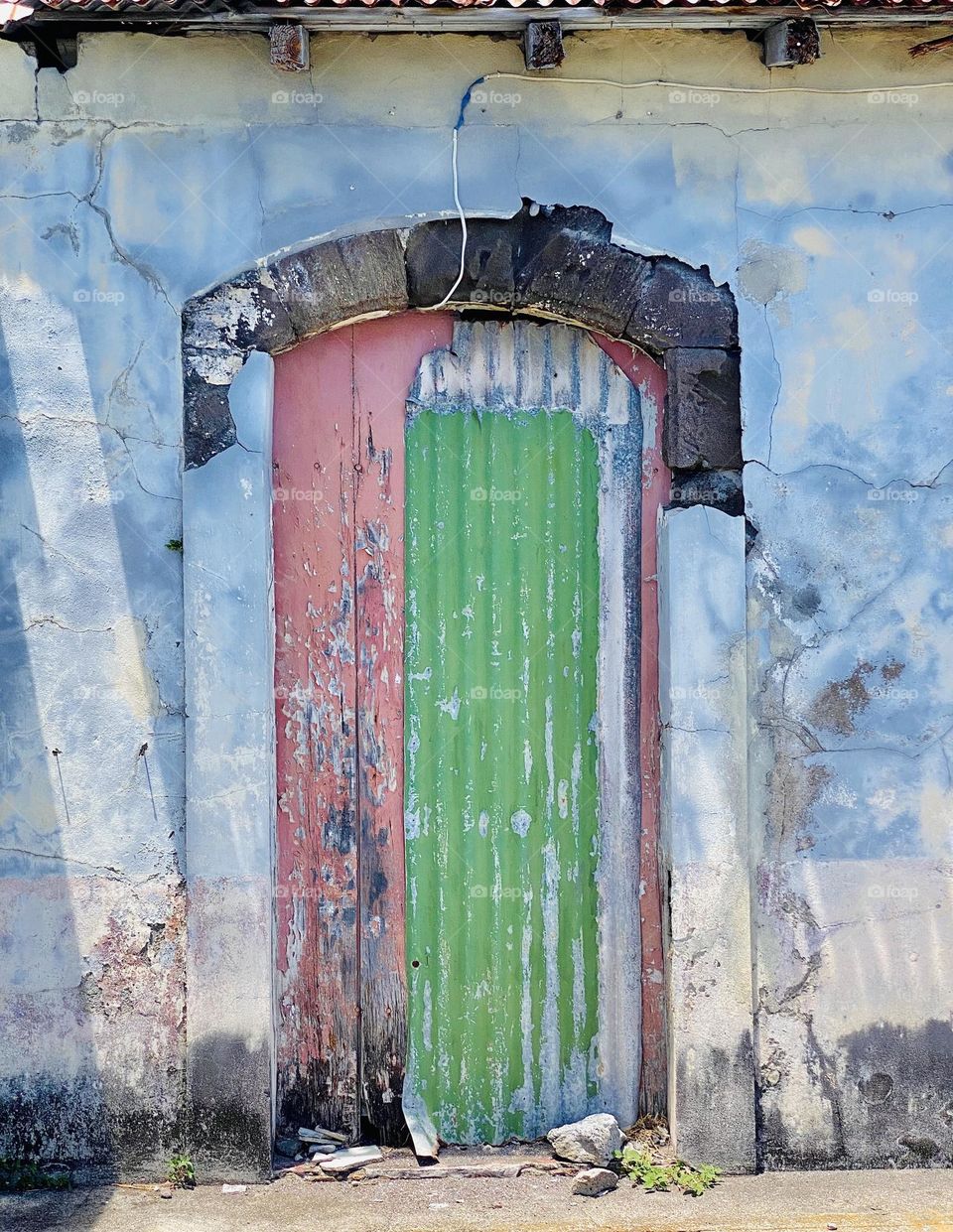 A green and red door in a blue painted building