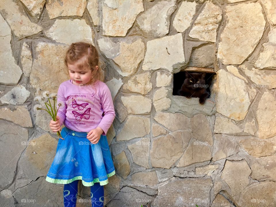 Cute girl with black kitty hiding in the wall 
