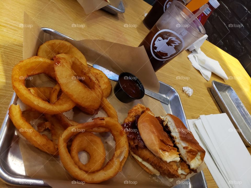Barbeque bacon cheddar chicken sandwich with onion rings.