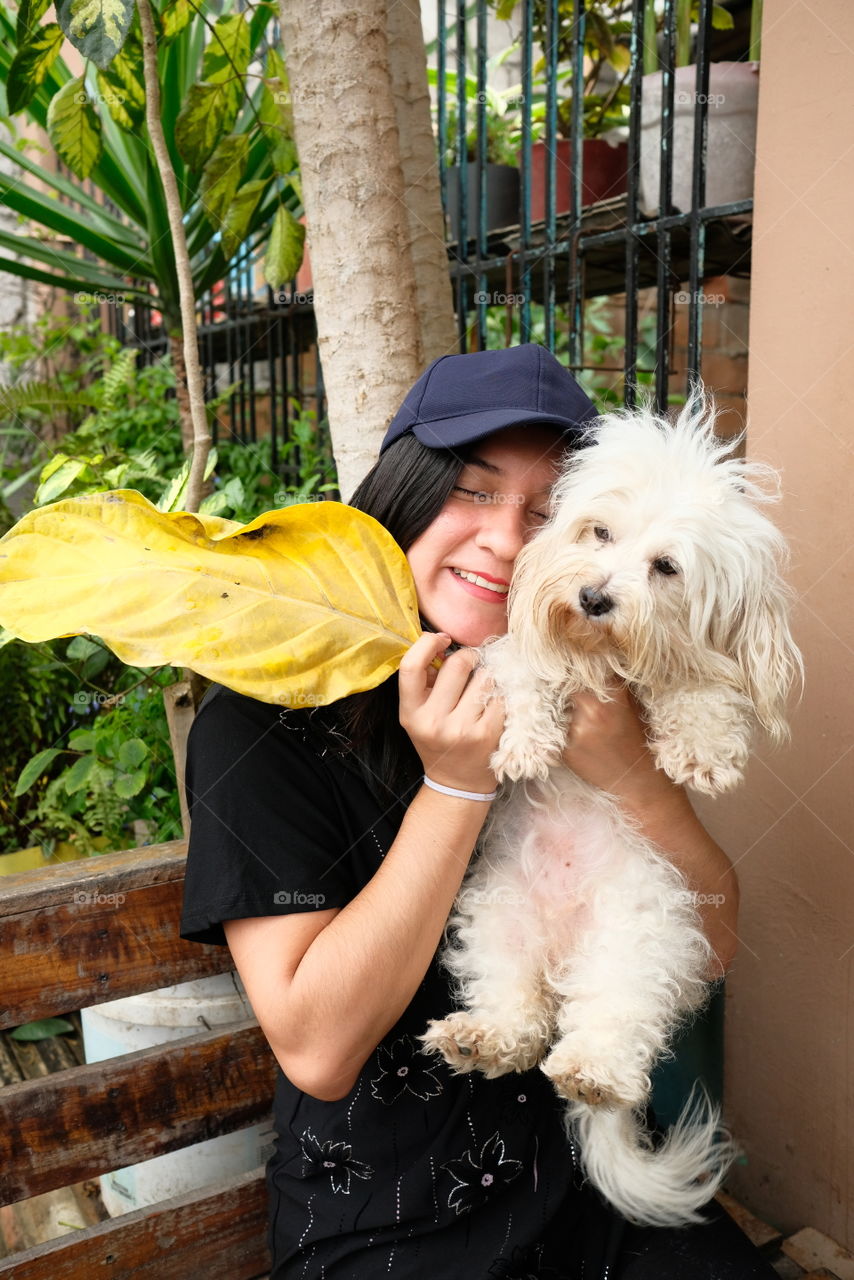 Young woman happy and smiling for the company of a white dog. She smiles hugging her dog and is happy with her pet.