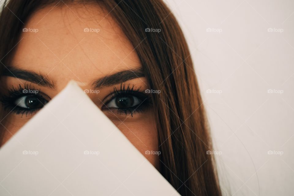 face of a woman hidden behind, eyes looking at you