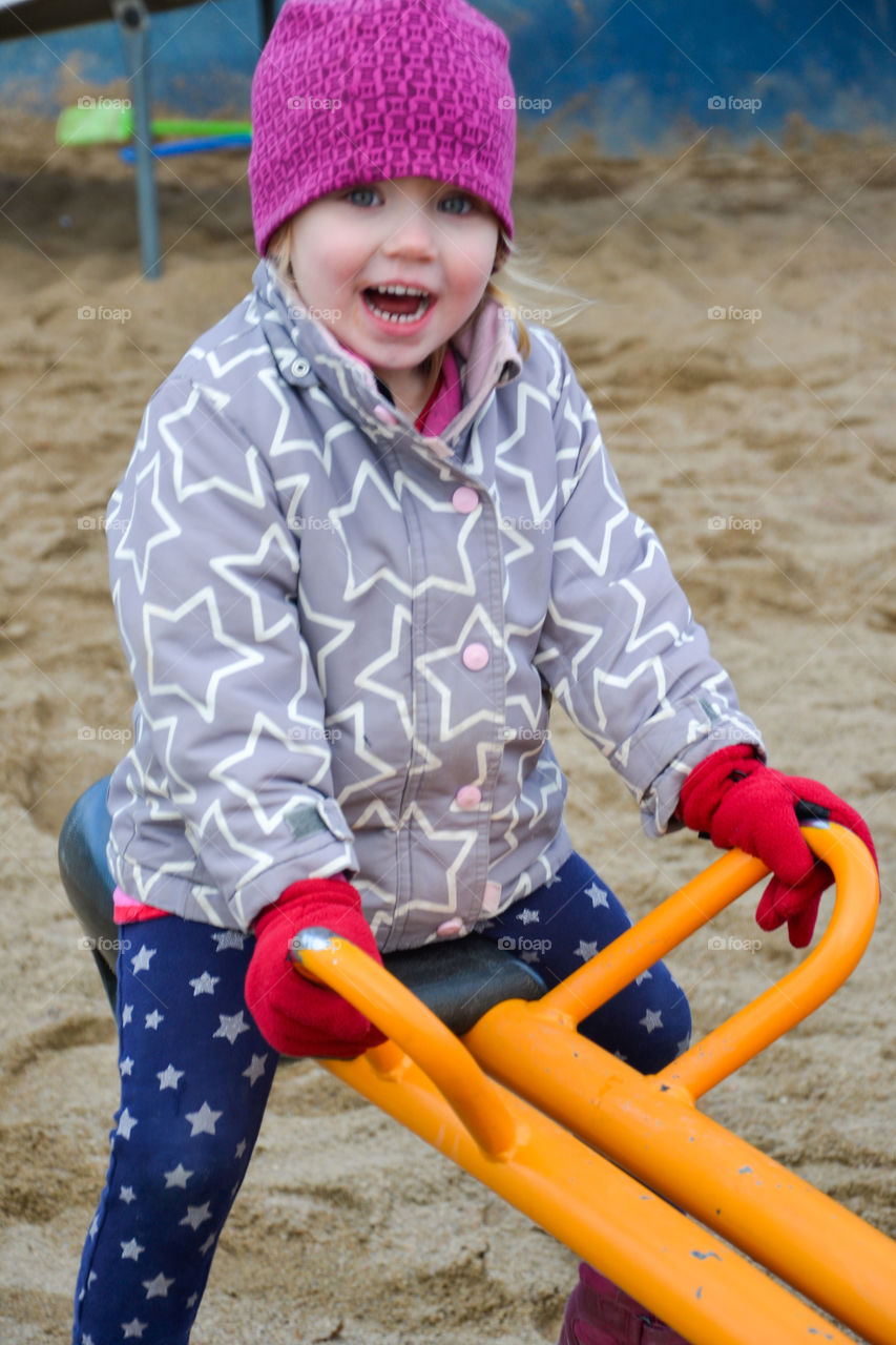 Little girl sitting on see-saw