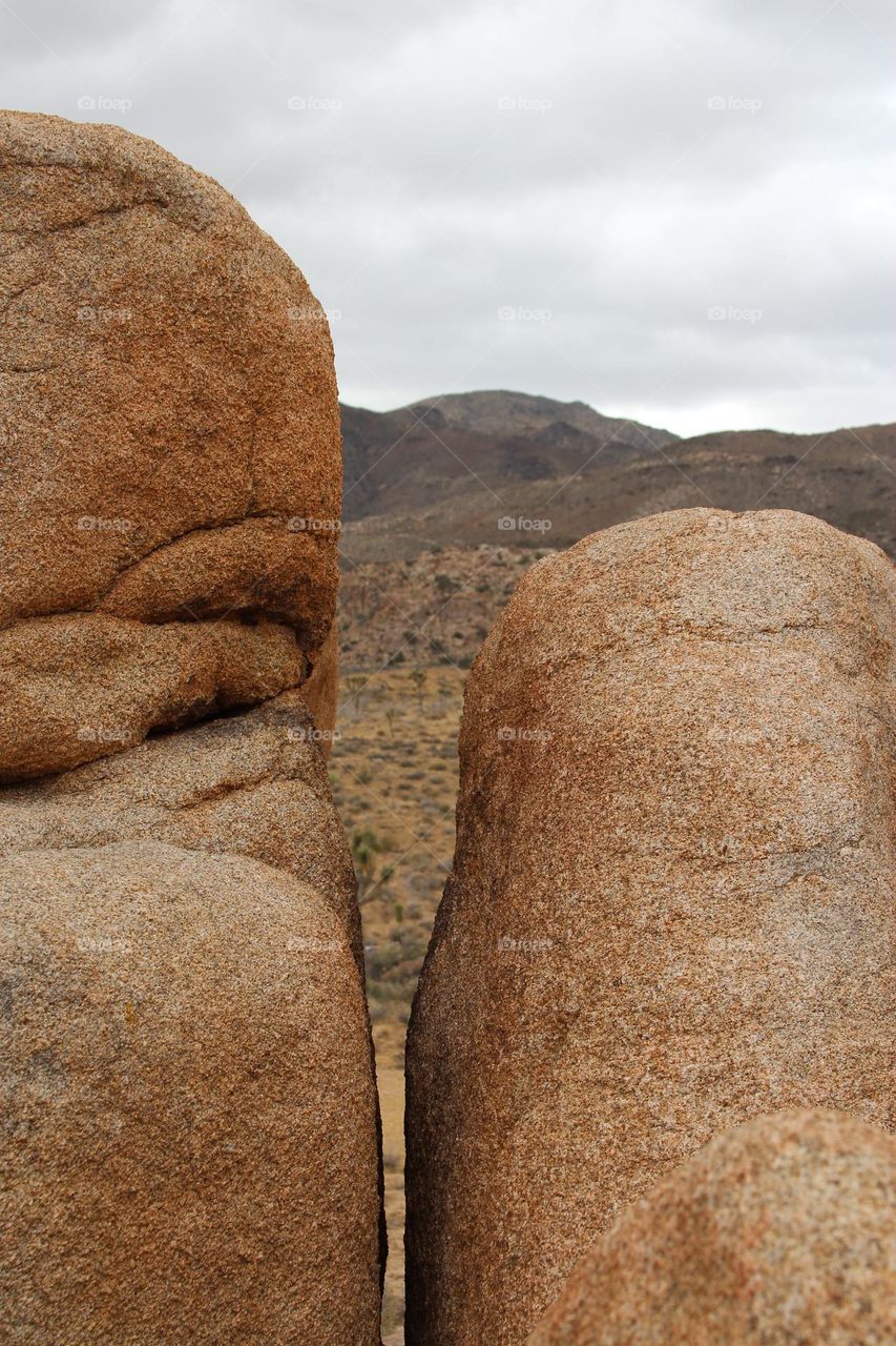 Stunningly beautiful rock formations at Joshua Tree National Park in California, with a cloud cover in the sky , looking through two boulders 