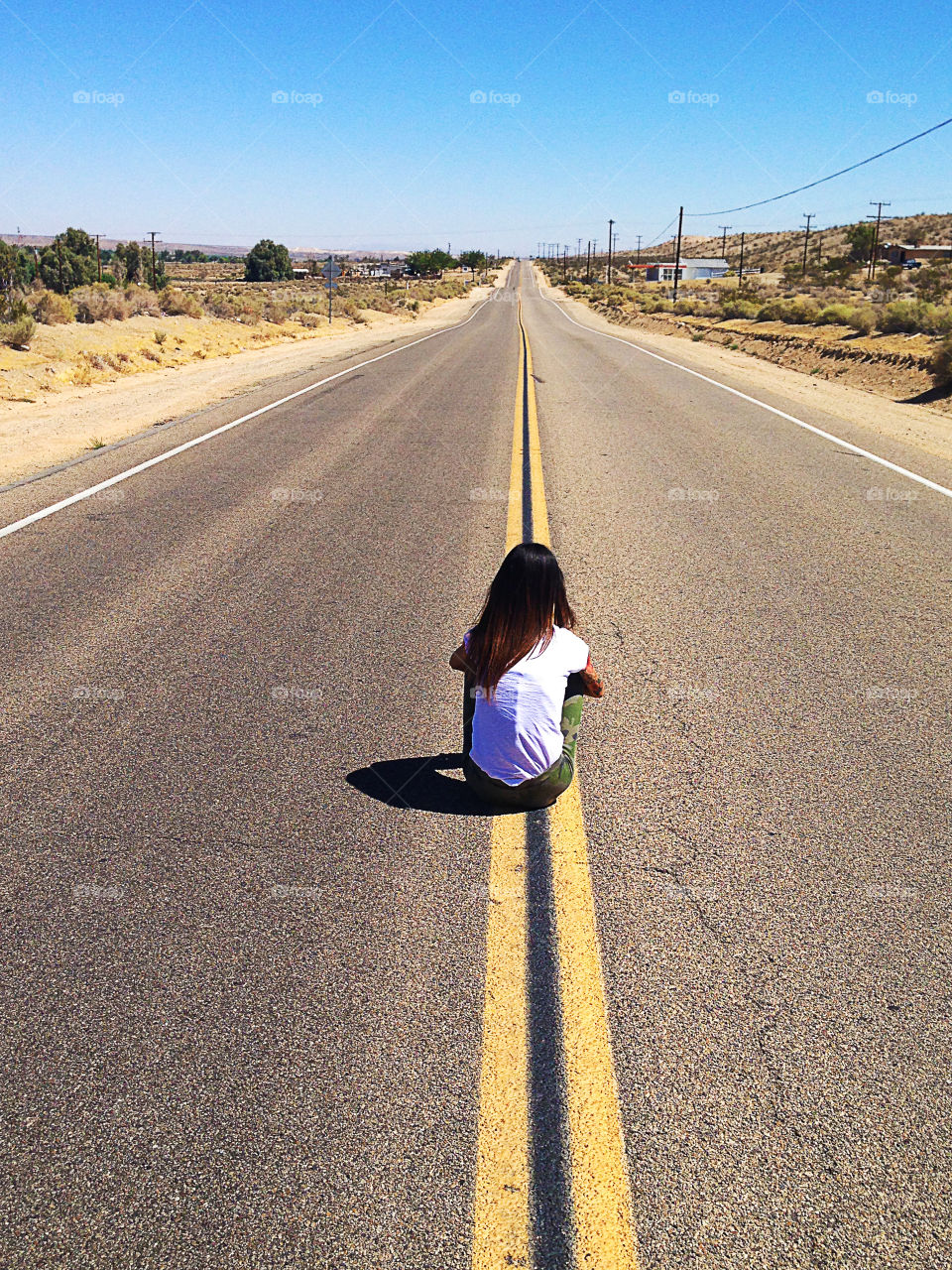 A small girl sitting on the long american road