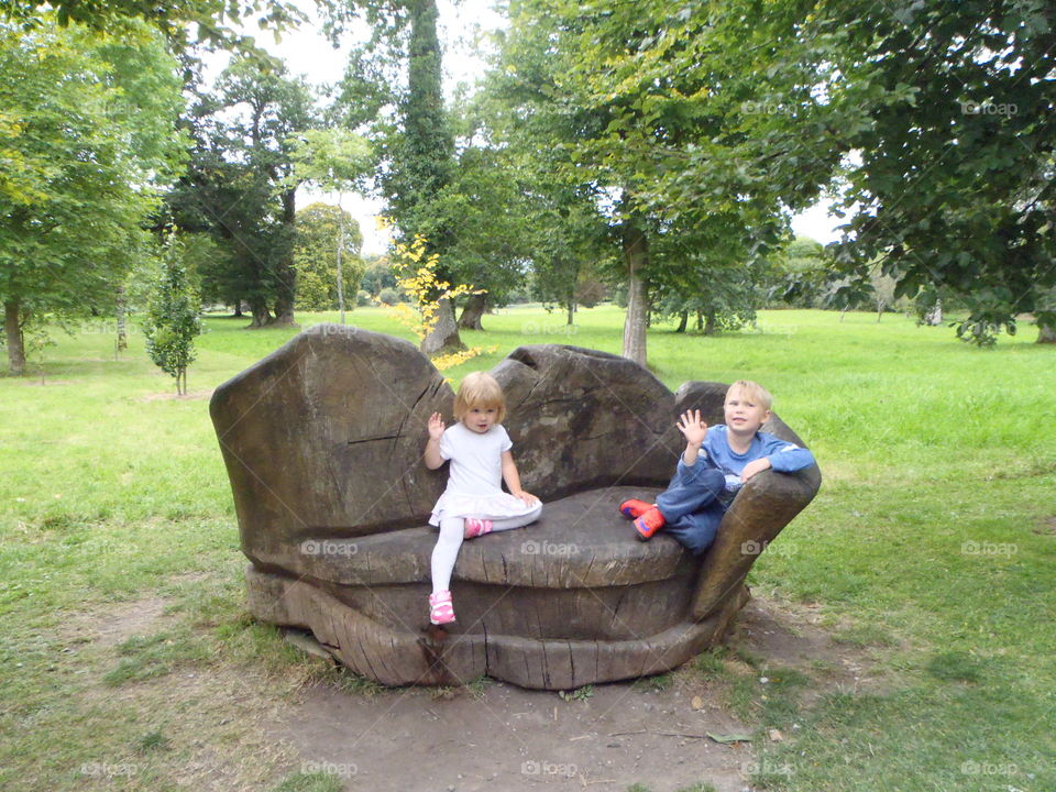 Girl and boy sitting on wooden carved bench