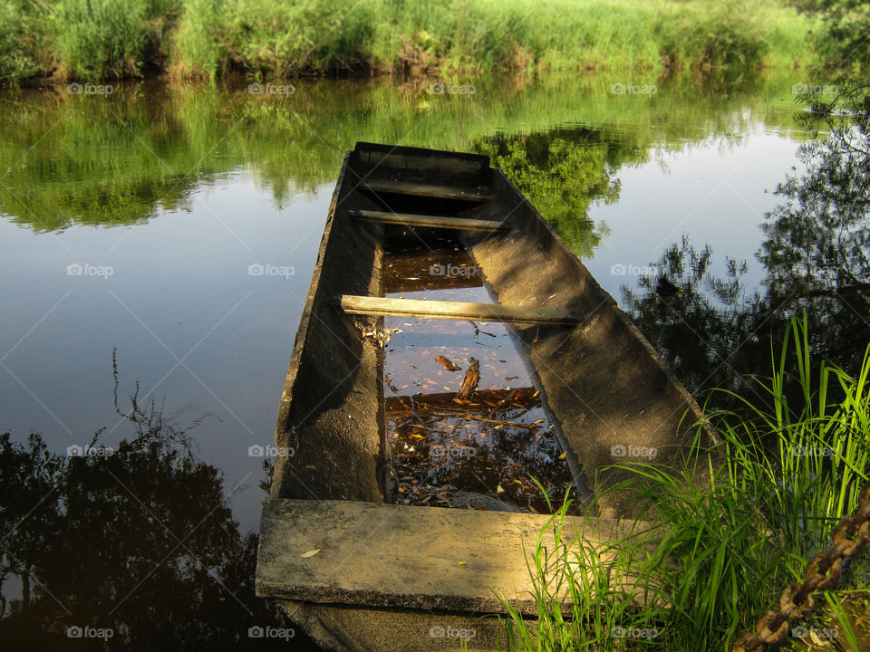 Abandoned boat near the overgrown riverbank