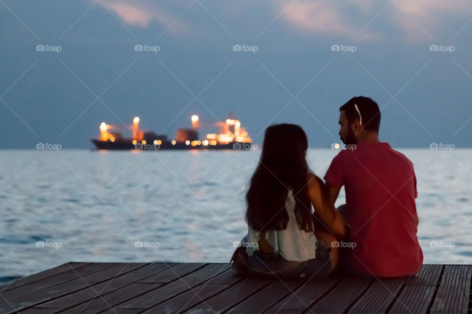 Couple In Love Sitting At The Dock Talking And Enjoying The Night View
