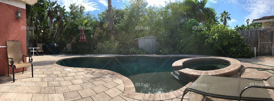 Panorama of a backyard summer home with a pool and hot tub in Indian Rocks Beach, FL