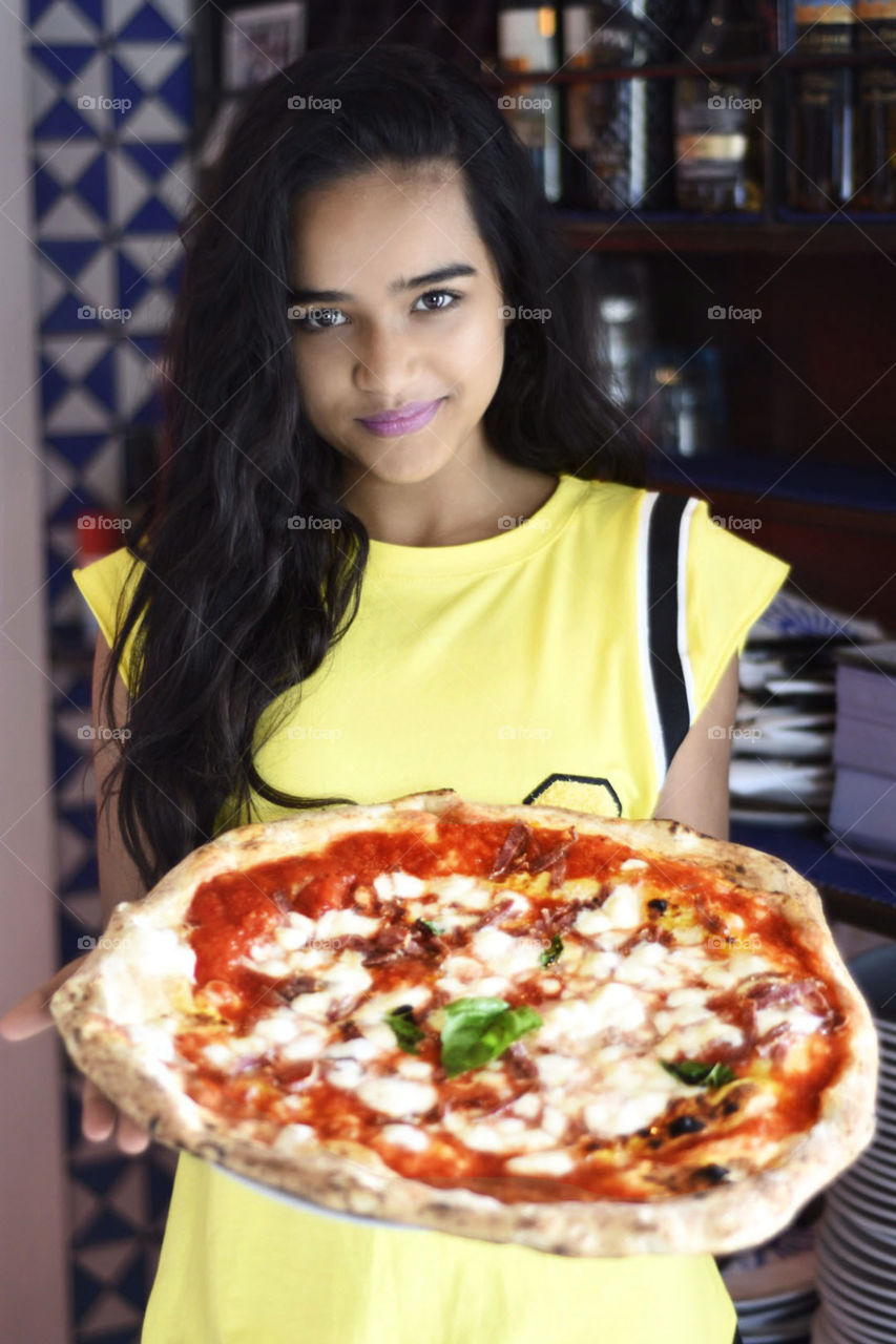 Young woman holding fresh pizza