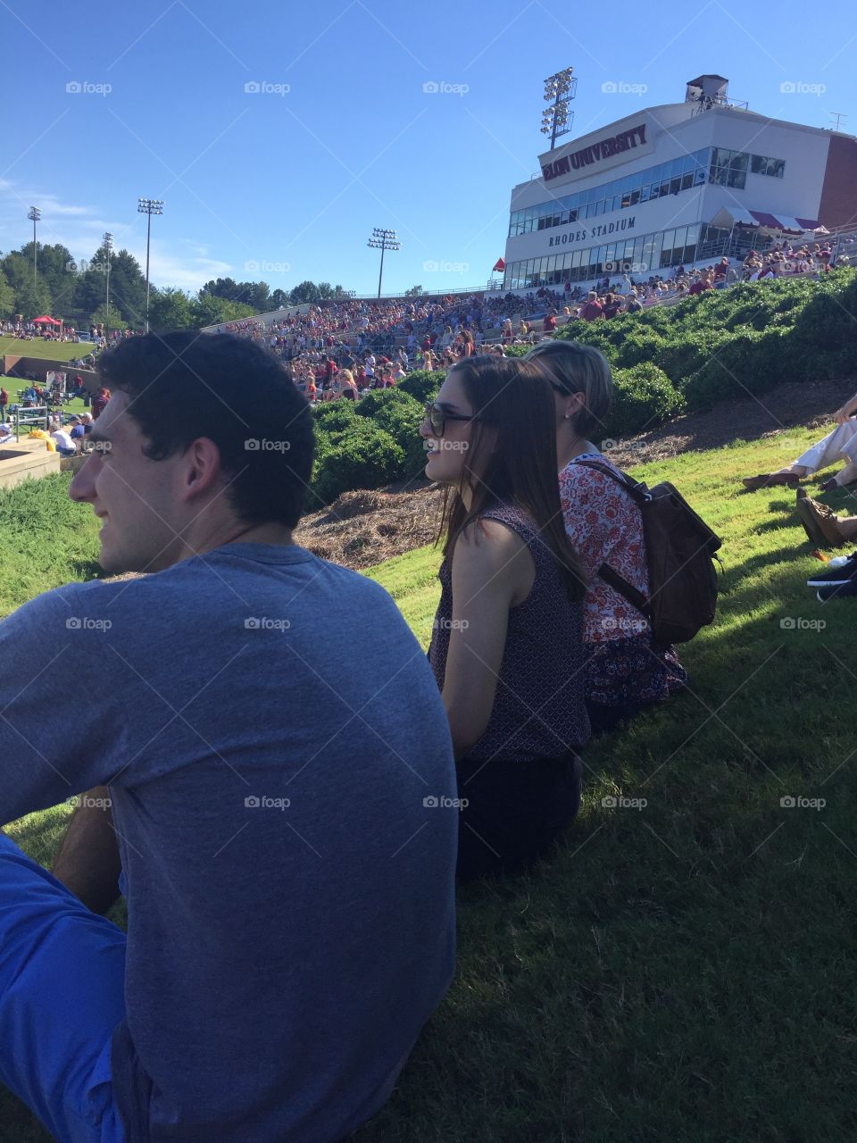Fall football game college watching from grassy area friends side view 