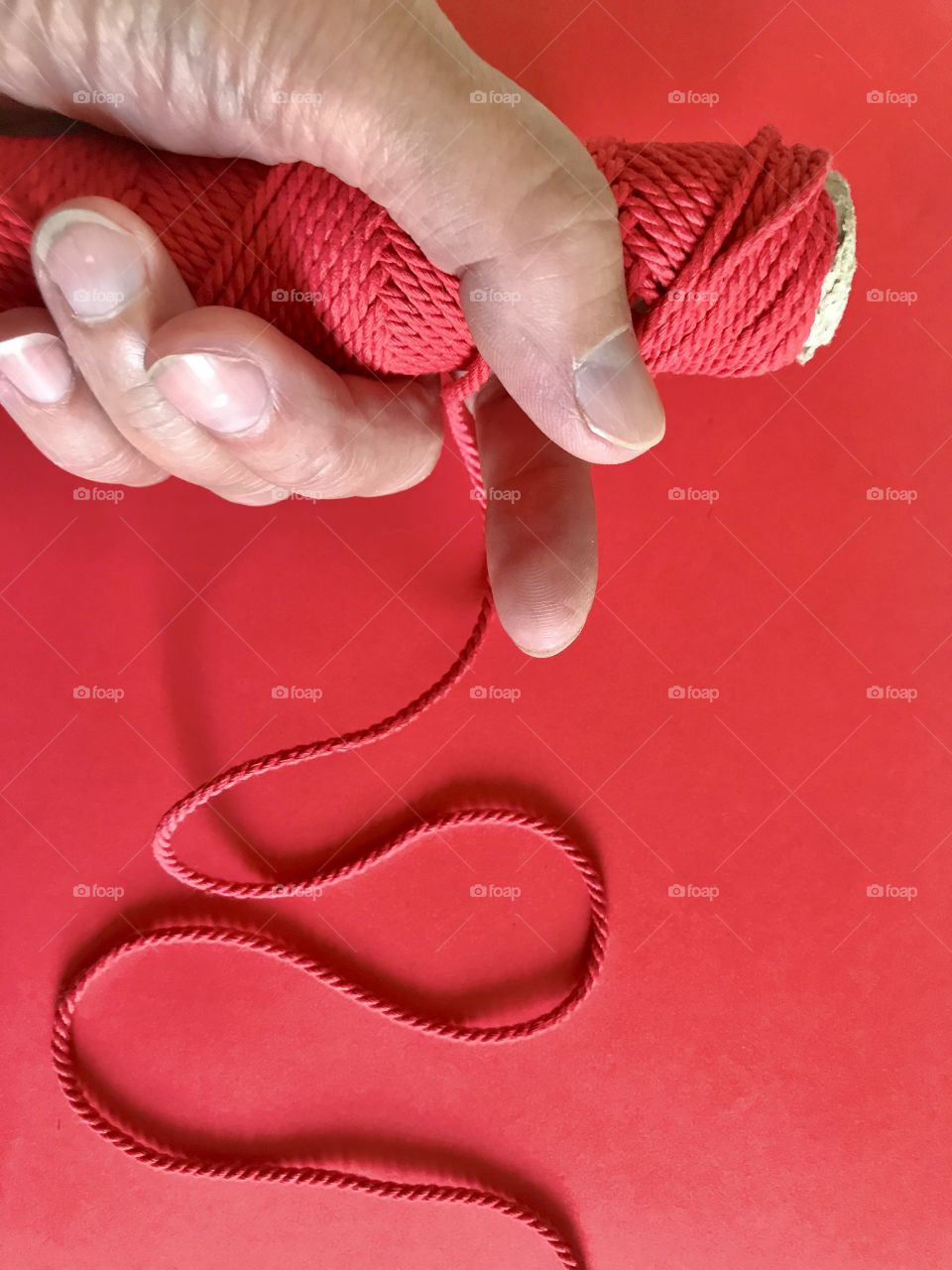 Red string in hand on red background