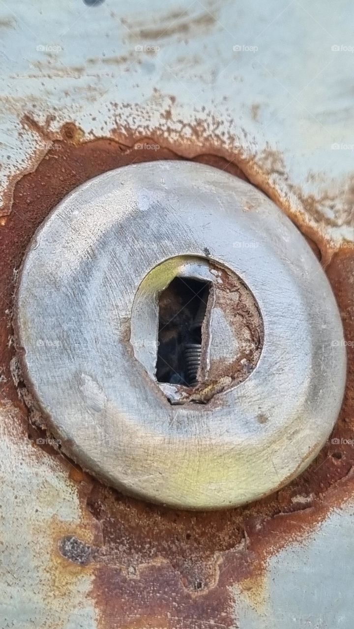 close-up of the circular door lock on a rusted truck.