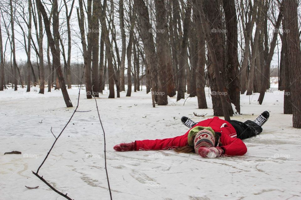 Girl laying on the ice in winter