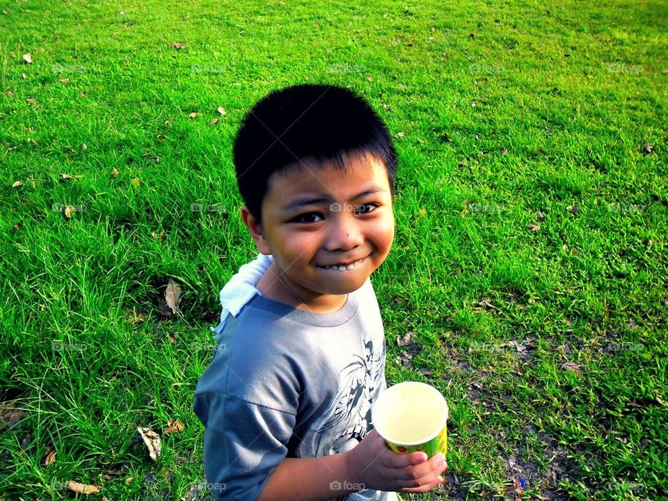 Little boy with drink and in a grassy field