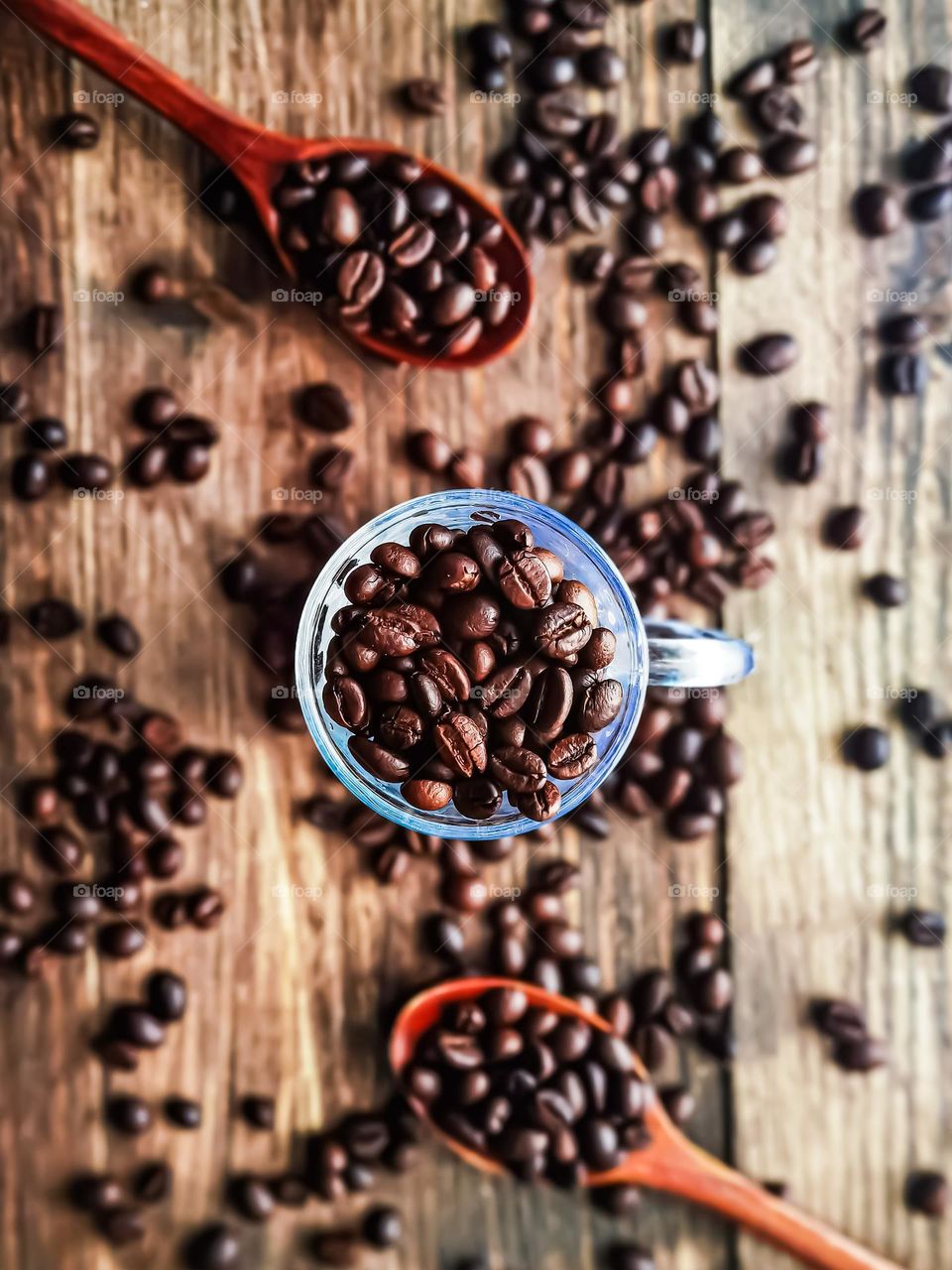 Coffee beans in a cup and scattered on a wooden table view from top