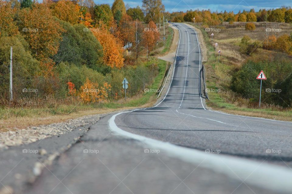 road in the middle of autumn landscapes with colorful trees.