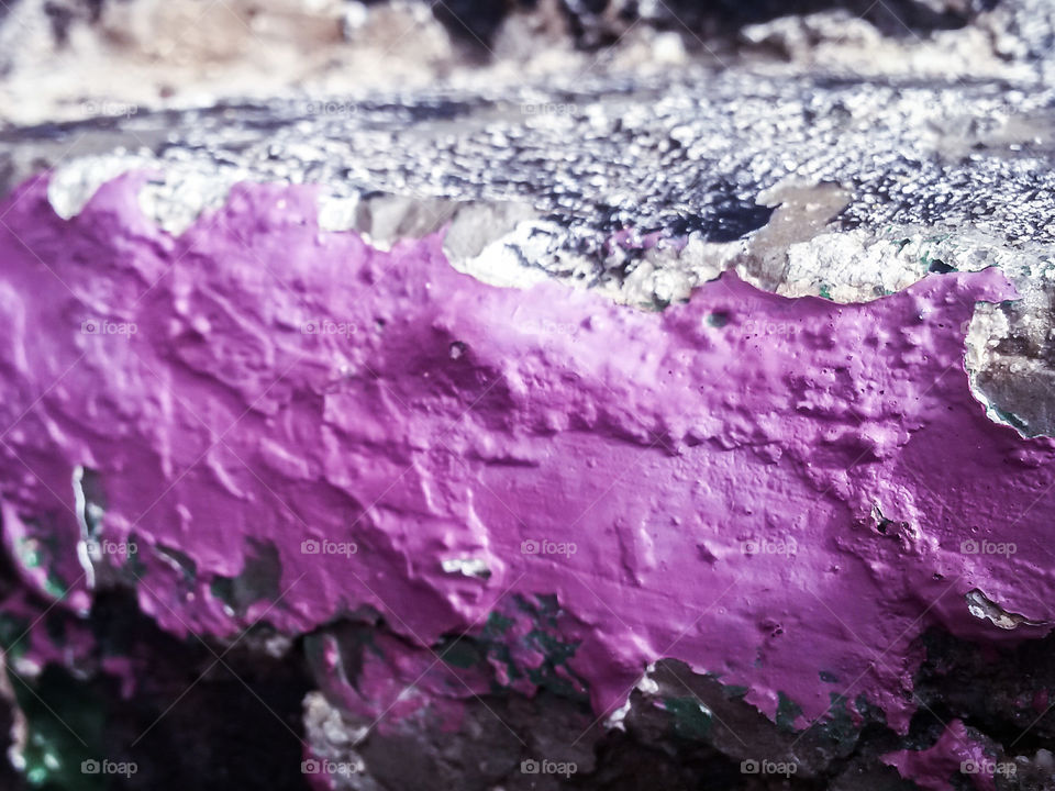 detail of a granite wall in an old building painted with purple color